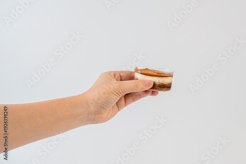 Wallpaper Mural Three-layered brownie cake topped with crunchy topping in a clear cup and hand. Torontodigital.ca