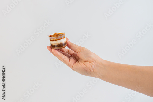 Wallpaper Mural Three-layered brownie cake topped with crunchy topping in a clear cup and hand. Torontodigital.ca