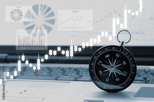 パソコンの上に置かれた方位磁針と株価のチャート