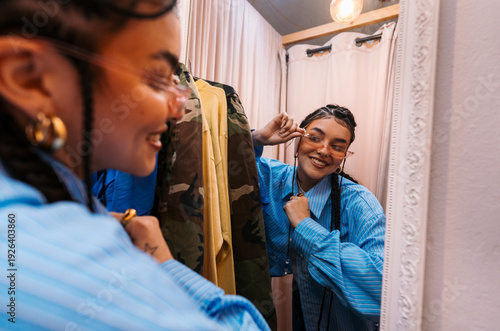 Young Woman Evaluates Sunglasses Cheerfully. Girl Examines Eyewear With Bright Smile In Front Of Mirror