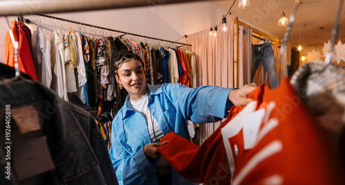 Customer Selects Coat. Shoppers Are Immersed In Browsing And Feeling Different Styles Of Clothing Items
