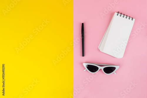 Wallpaper Mural Fashionable sunglasses with a notebook and stationery, against a yellow and pink background. Torontodigital.ca