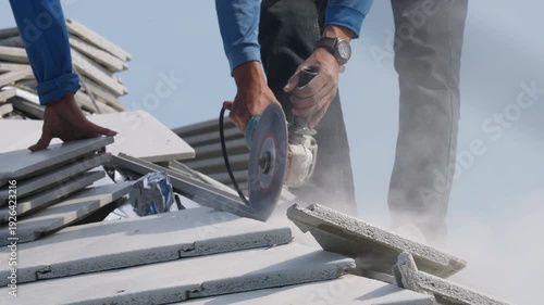 Construction worker cutting concrete board using angle grinder at building site. Industrial renovation process, power tool operation and structural installation concept.