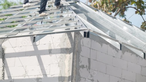Steel roof frame installed on concrete block wall of unfinished building. Residential construction site, structural engineering and housing development concept.
