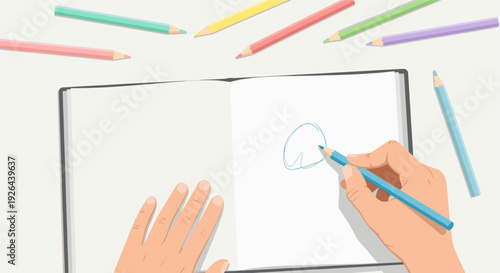 Overhead shot of a hand drawing a blue circle in an open sketchbook, with colored pencils scattered around it. Flat lay style with bright, clean aesthetic for creative projects.