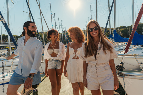 Εκτύπωση καμβά Four friends smiling and walking on a marina dock during a sunny summer sailing