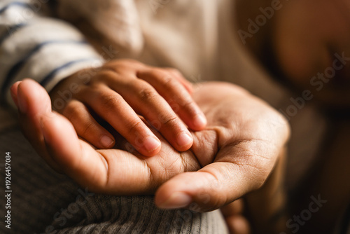 Obraz na płótnie Close up of mother holding hands of hispanic baby toddler with sof light