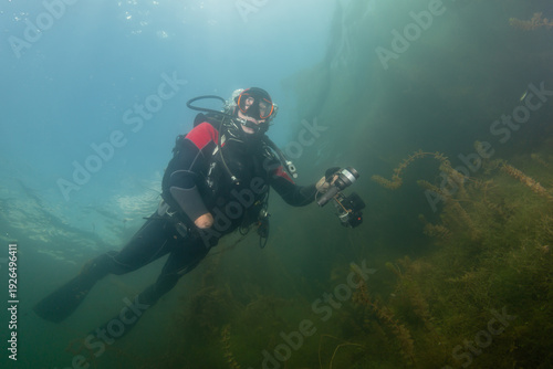 Wallpaper Mural Older diver explore underwater site and capture moments using cameras during a diving session in clear water Torontodigital.ca