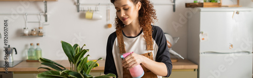 Photography Curly young woman enjoying a blissful moment while cleaning her cozy apartment