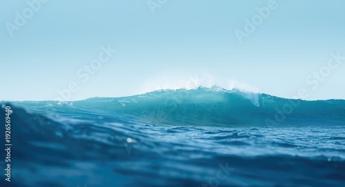 Ocean waves with gradient blue hues under a bright sky with designated copy space