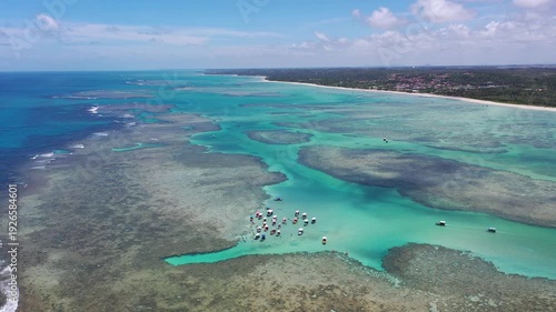 Amazing view of dozens of small boats in the natural pools among the coral reefs of Milagres beach near Maceio city, coast of Brazil 