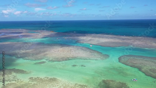 Amazing view of dozens of small boats in the natural pools among the coral reefs of Milagres beach near Maceio city, coast of Brazil 