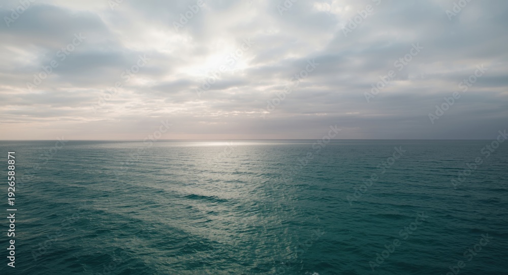 Fototapeta premium Vast ocean under a cloudy sky with soft sunlight