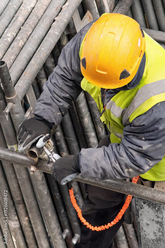 construction workers with safety equipment assembling scaffolding for maintenance of building facade on city street