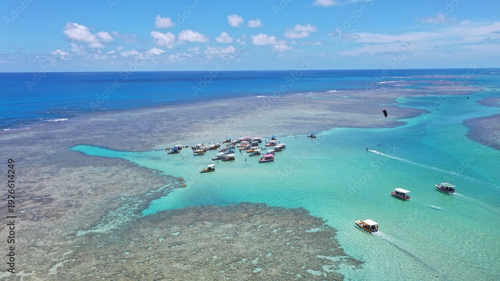 Obraz premium Fantastic aerial view of the turquoise waters of Toque beach with dozen of small boats with tourists on the natural pools formed among coral reefs in Milagres route near Maceio, Alagoas State, Brazil 