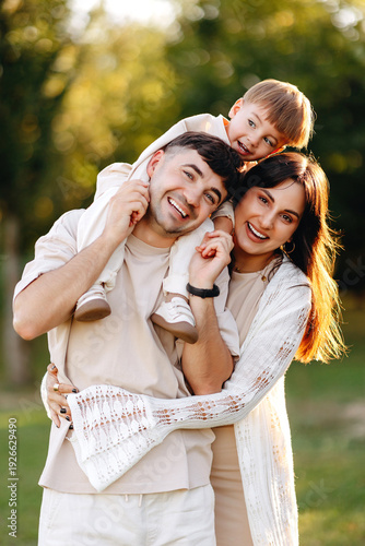 Happy Young Family Portrait in Park With Smiling Parents and Child Enjoying Outdoor Time
