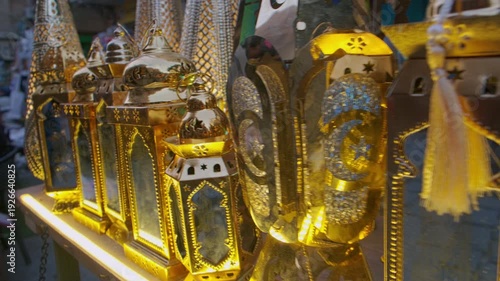 Decorative metal Ramadan lanterns illuminated with warm golden light inside stand on traditional market stall. Khan El-Khalili bazaar in Cairo, Egypt