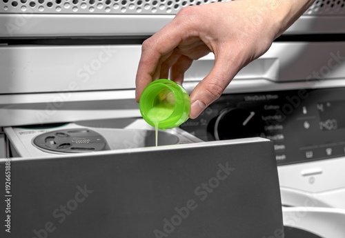 Wallpaper Mural Woman pouring liquid detergent into washing machine compartment from green cap. Adult female filling appliance drawer in laundry room. Domestic washing concept for home, household, lifestyle Torontodigital.ca