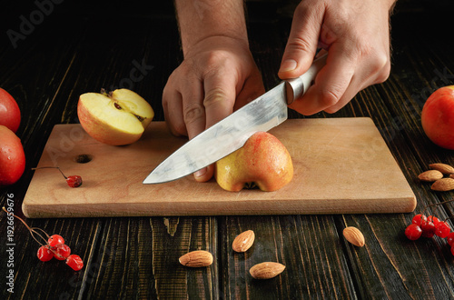 Fotografie A person is slicing fresh, red apples on a wooden cutting board