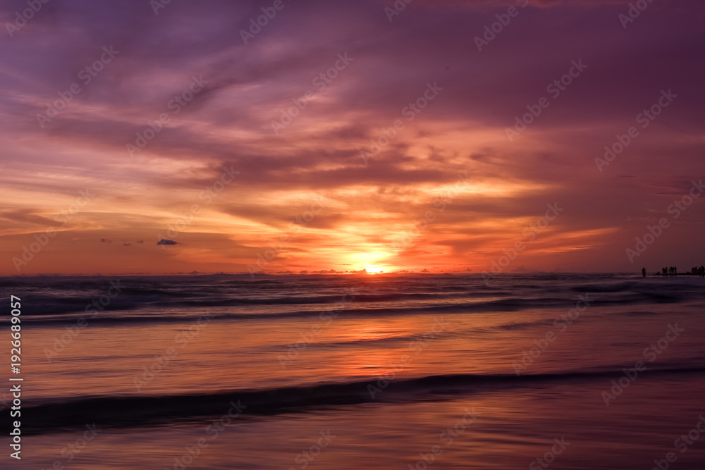 Obraz premium Dramatic colorful sunset seascape at Parangtritis Beach, Yogyakarta with ocean waves and silhouettes