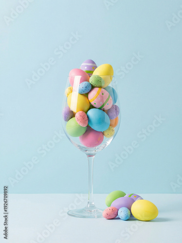 Wine Glass Filled with Colorful Easter Eggs on Light Blue Background – Minimal Festive Concept