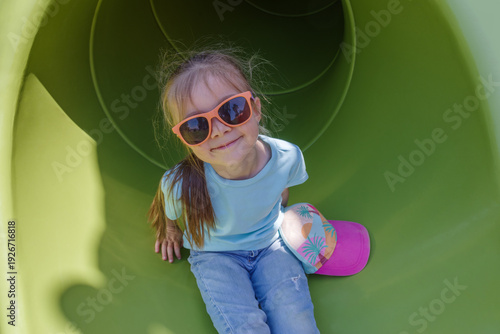 Girl having fun in tube slide on playground