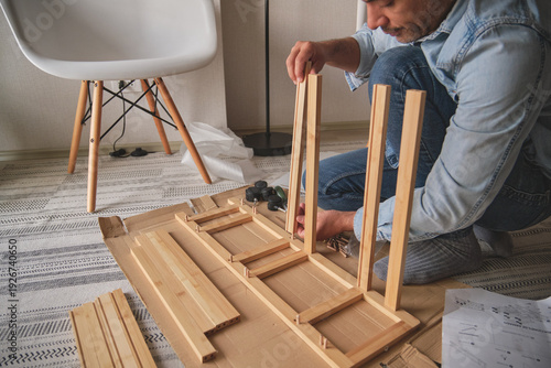 Canvastavla Man assembling new flat-pack wooden furniture on a cardboard box at home