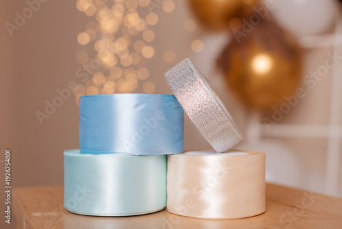 Stacked satin ribbon rolls with festive bokeh