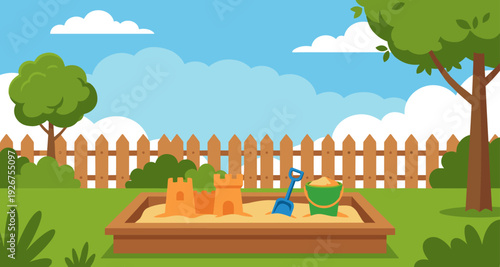 Children's wooden sandbox with a sandcastle, shovel, and bucket sitting on a green lawn in a sunny backyard with a fence and trees under a blue sky