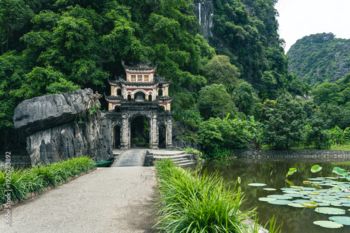Stone bridge and ornate gate of Bich Dong Pagoda leading into a mountain cave in Ninh Binh