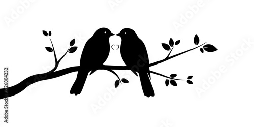 Two black birds perched on a branch facing each other in a loving pose