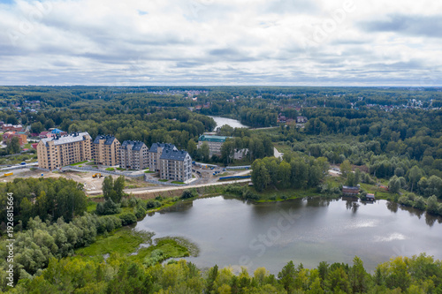 Aerial view of the construction of a small town surrounded by forests near a lake in Siberia