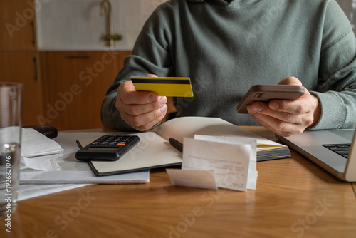 Εκτύπωση καμβά Man with credit card at his hand planning home budget at kitchen table with laptop and checks the money balance for calculating unpaid bills for rent, expensive utility payments and grocery invoices