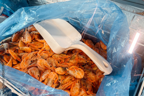 Schilderij op canvas A plethora of delicious frozen cooked shrimp in a large blue plastic bag with a