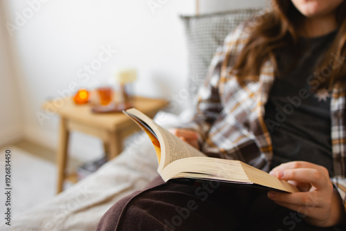 Person relaxing on bed reading book at home