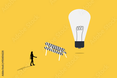 Business woman walking toward a giant lightbulb behind a road barrier, representing overcoming obstacles, persistence, and reaching for creative innovation