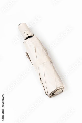 Folded biege automatic umbrella isolated on white background