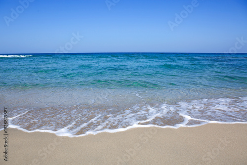 Sandy beach with blue sky and turquoise water .