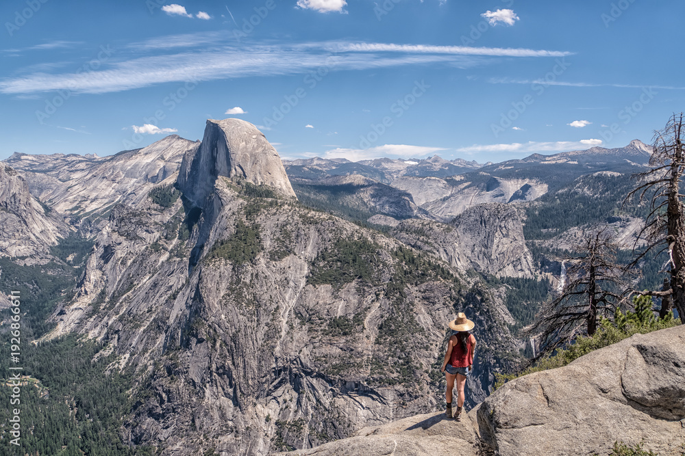 Fototapeta premium A woman is walking on a mountain top with a hat on