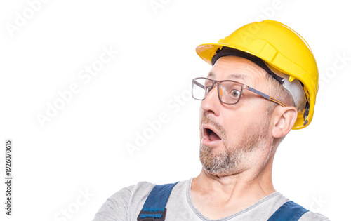 Afraid construction worker with popcorn looking to the side, isolated on white background. Scared repairman. Weekend times - movies watching concept. Craftsman against white wall