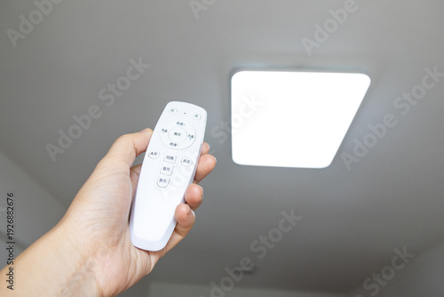 Tableau sur toile Adjusting a ceiling light with a remote