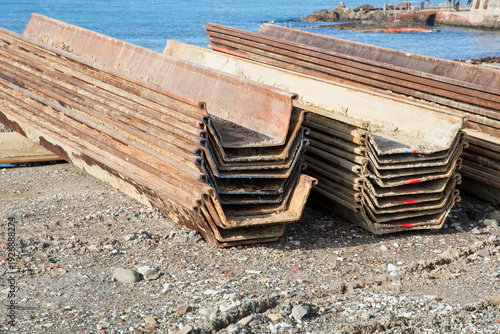 Fotografía STEEL SHEET PILING STACKED AT CONSTRUCTION SITE - Metal sheet pile elements for