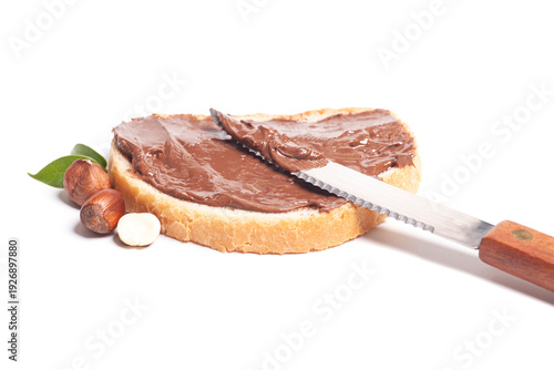 chocolate-nut paste spread on bread with knife, hazelnuts and leaves