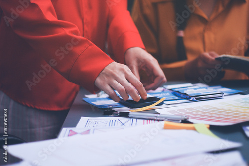 Team of uxui designers pointing at computer screen, discussing new mobile app design in the office