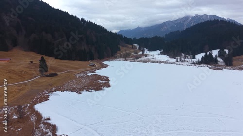 Blick von oben auf den verschneiten Geroldsee Wagenbruechsee. Top-Touristenziel in der Gemeinde Kruen Oberbayern. Winterlandschaft mit Bergen und gefrorenem Alpensee.