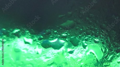 Green glowing underwater scene with bubbles rising in dark water with a rocky seabed