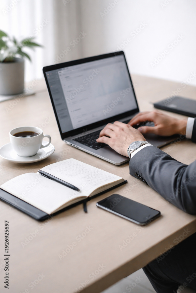 Fototapeta premium Profissional trabalhando em laptop em mesa de escritório com café, caderno e smartphone