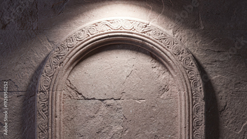 Ancient carved stone archway illuminated by a single ray of light in a historic setting