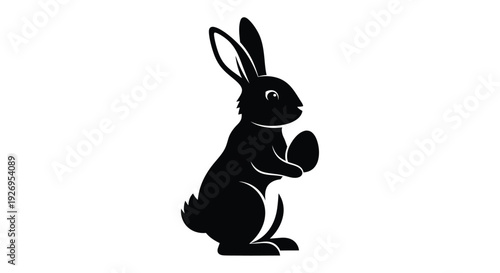 Black silhouette of an Easter bunny holding a decorated egg stands ready for the springtime holiday.
