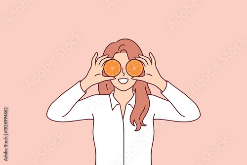 Smiling girl covers her eyes with fresh oranges to promote a healthy, balanced, and organic diet. Concept of mindful nutrition, natural vitamins, and a joyful approach to ecological food choices.